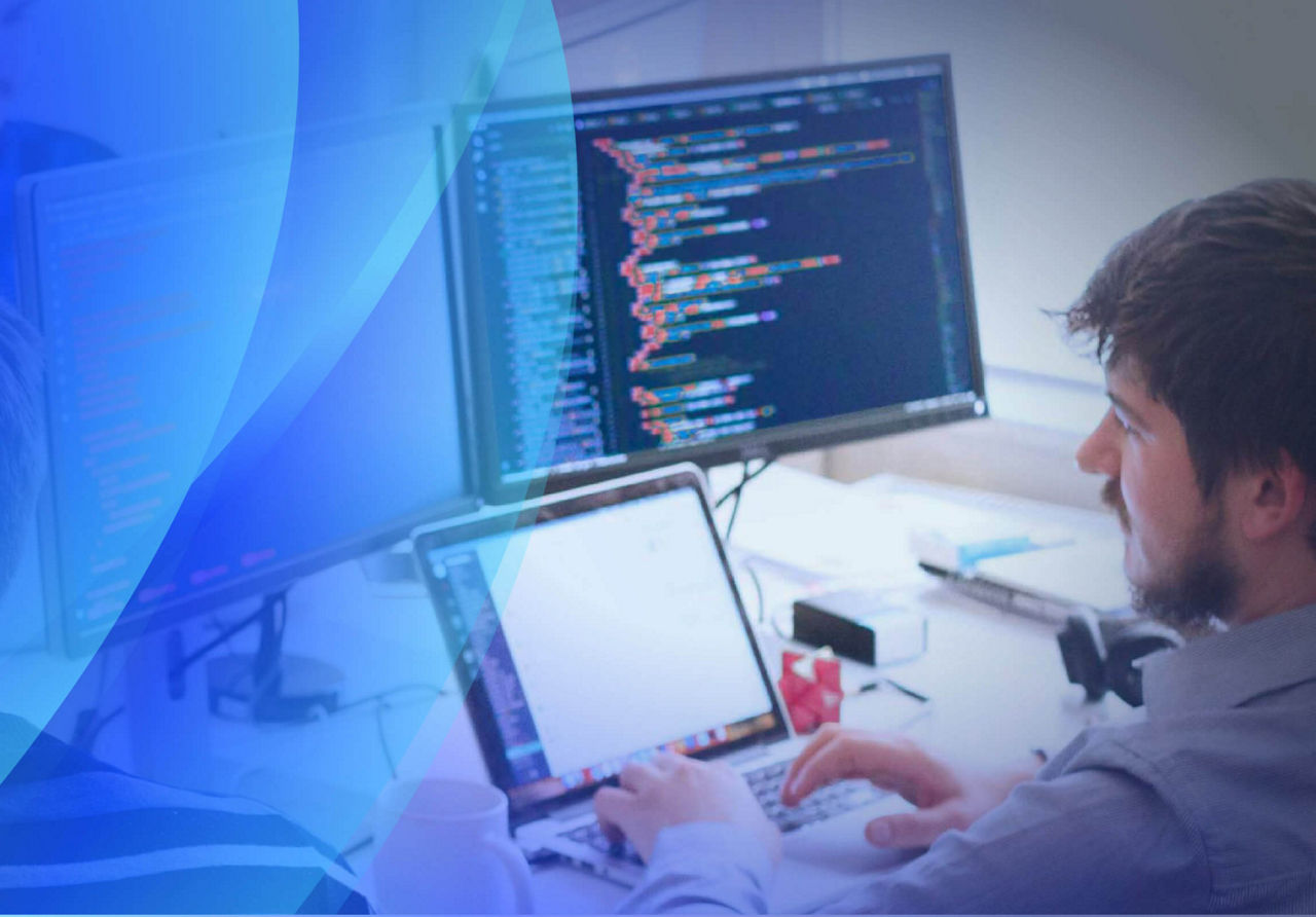 Man in front of computer screen reading code