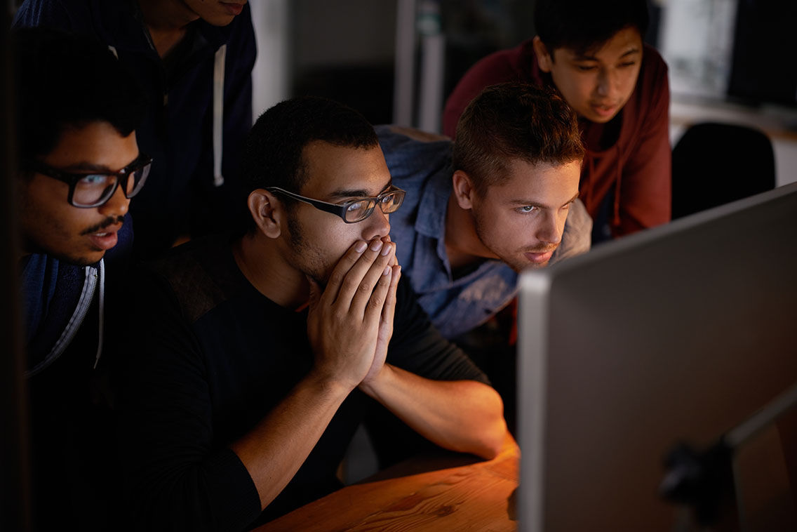 concerned men leaning into a computer screen