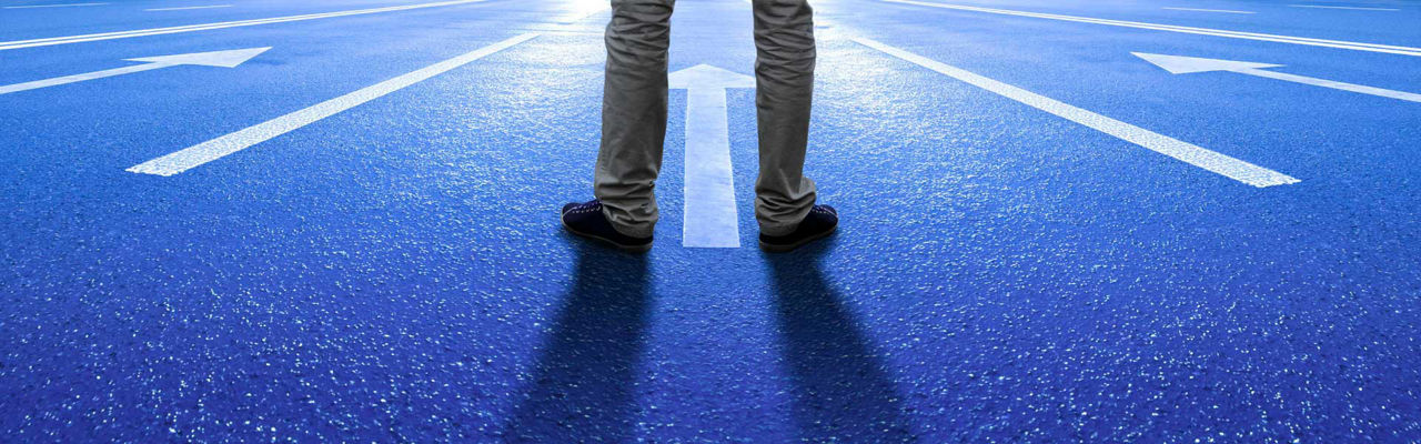 A man standing in front of arrows pointing in a new direction
