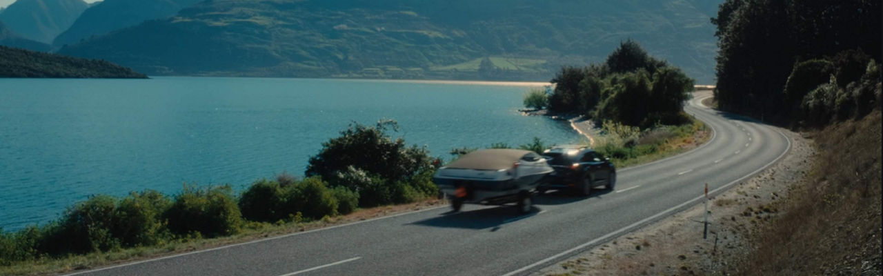 Car with boat attached driving a scenic route 