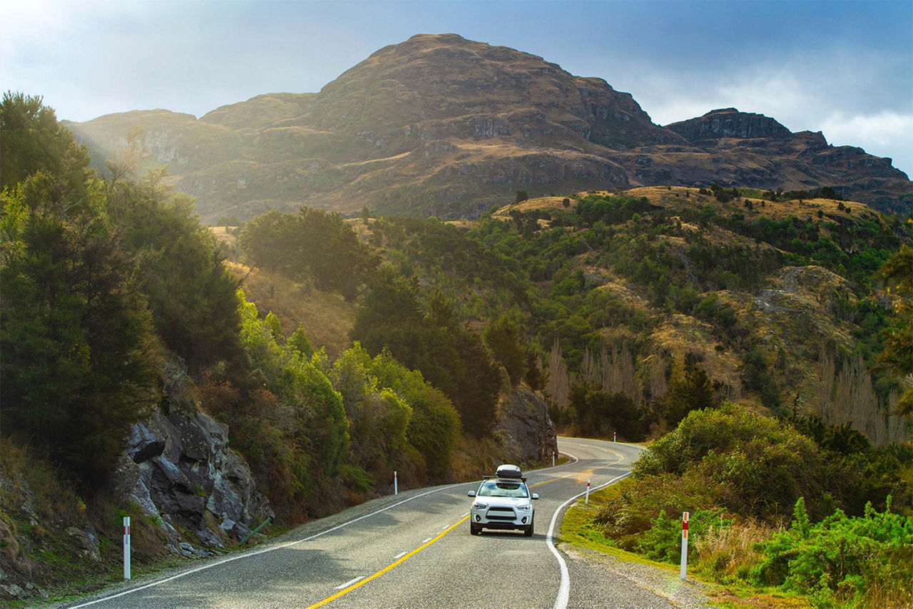 A white car driving on a scenic hilly road